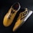 A pair of yellow and black sports shoes displayed against a dark background. The shoes feature a bold geometric pattern and are designed for athletic performance.
