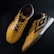 A pair of yellow and black sports shoes displayed against a dark background. The shoes feature a bold geometric pattern and are designed for athletic performance.